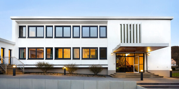 Die abendliche Außenaufnahme zur goldenen Stunde. Das Architekturfoto zeigt das Gebäude eines Anbieters für Ferienwohnungen in der Eifel. © Architekturfotograf Dirk Baumbach.